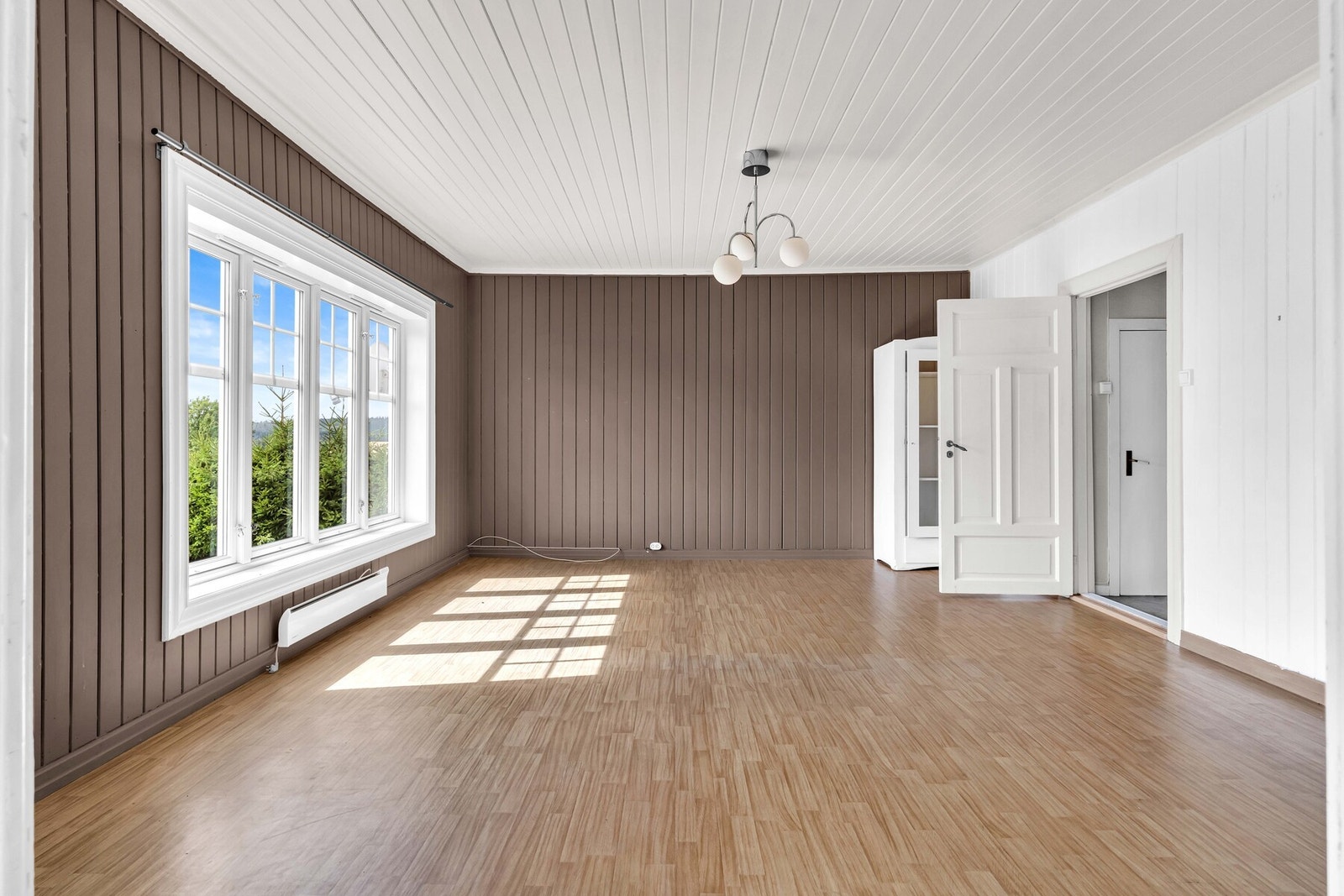 Rommet er malt i hvitt og en mørk jordnyanse, og en gammel etasjeovn bidrar til et sjarmerende uttrykk. Galleribilde