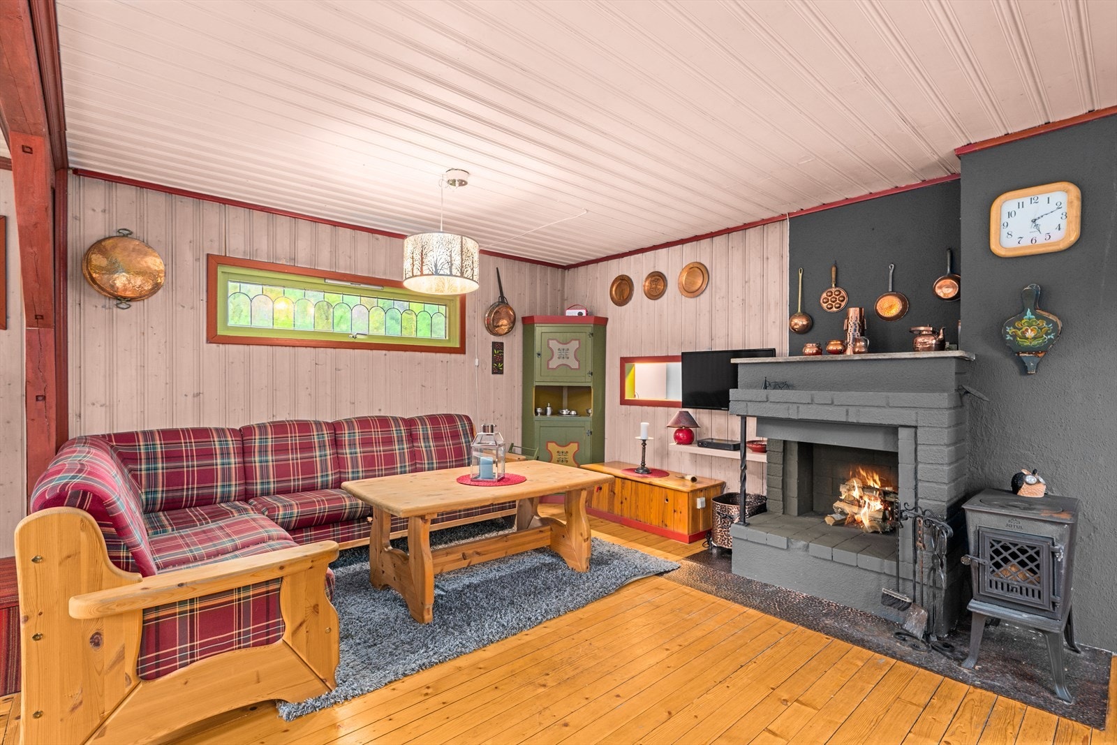 Hytta har en koselig stue med peis Galleribilde