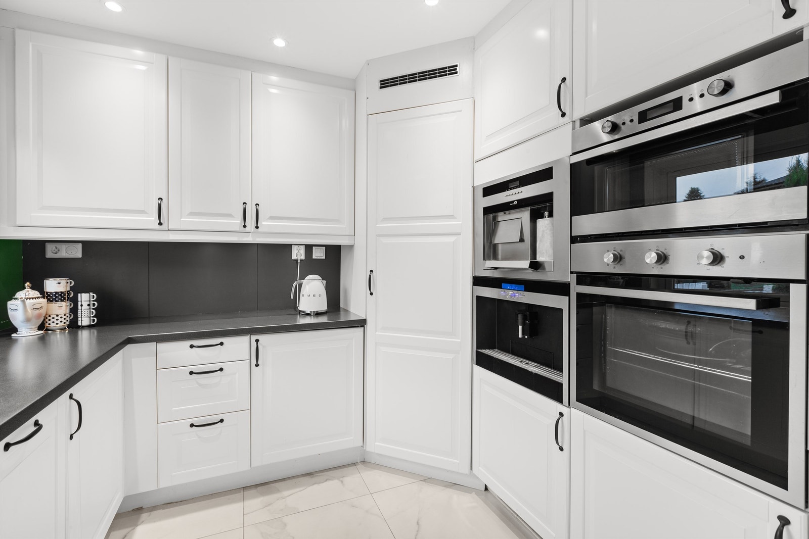 Klassisk kjøkken med hvite, profilerte fronter og integrerte hvitevarer Galleribilde