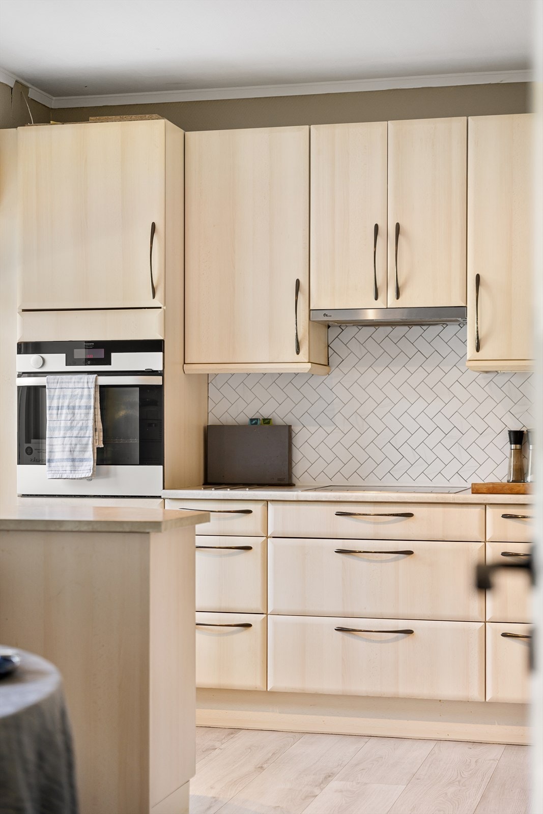 Selvklebende fliser med flismønster og belysning mellom skapene gir kjøkkenet et stilfullt preg. Galleribilde