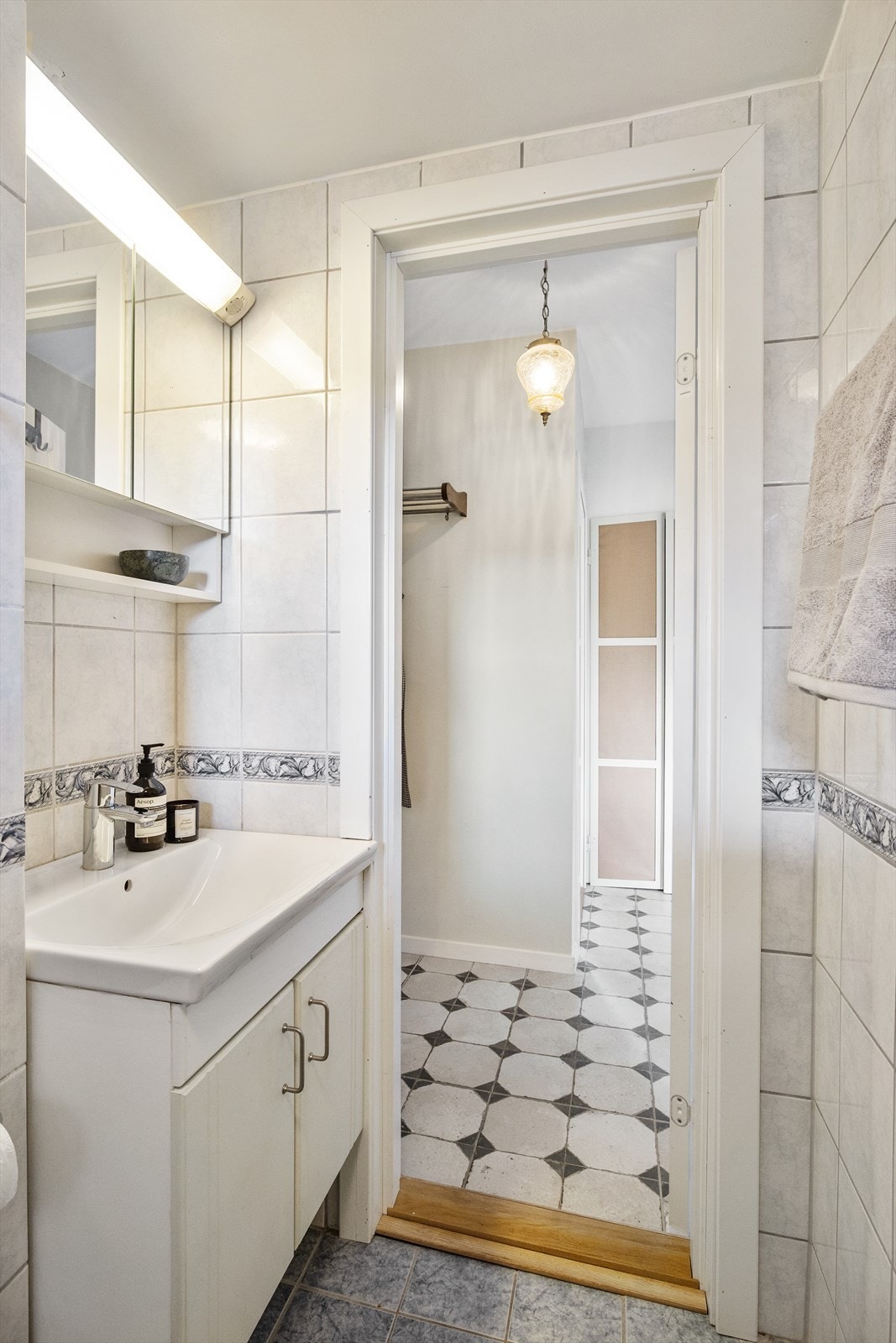 Badet inneholder dusjhjørne, toalett og baderomsinnredning med skuffer, servant med ett-greps blandebatteri og vegghengt speilskap med belysning. Det er plass til både vaskemaskin og tørketrommel, samt plassbygde hyller. Galleribilde