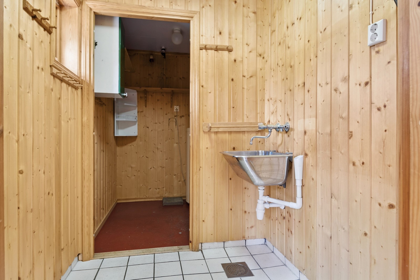 Praktisk vaskerom med flislagt gulv, opplegg for vaskemaskin og videre adkomst til teknisk rom. Galleribilde