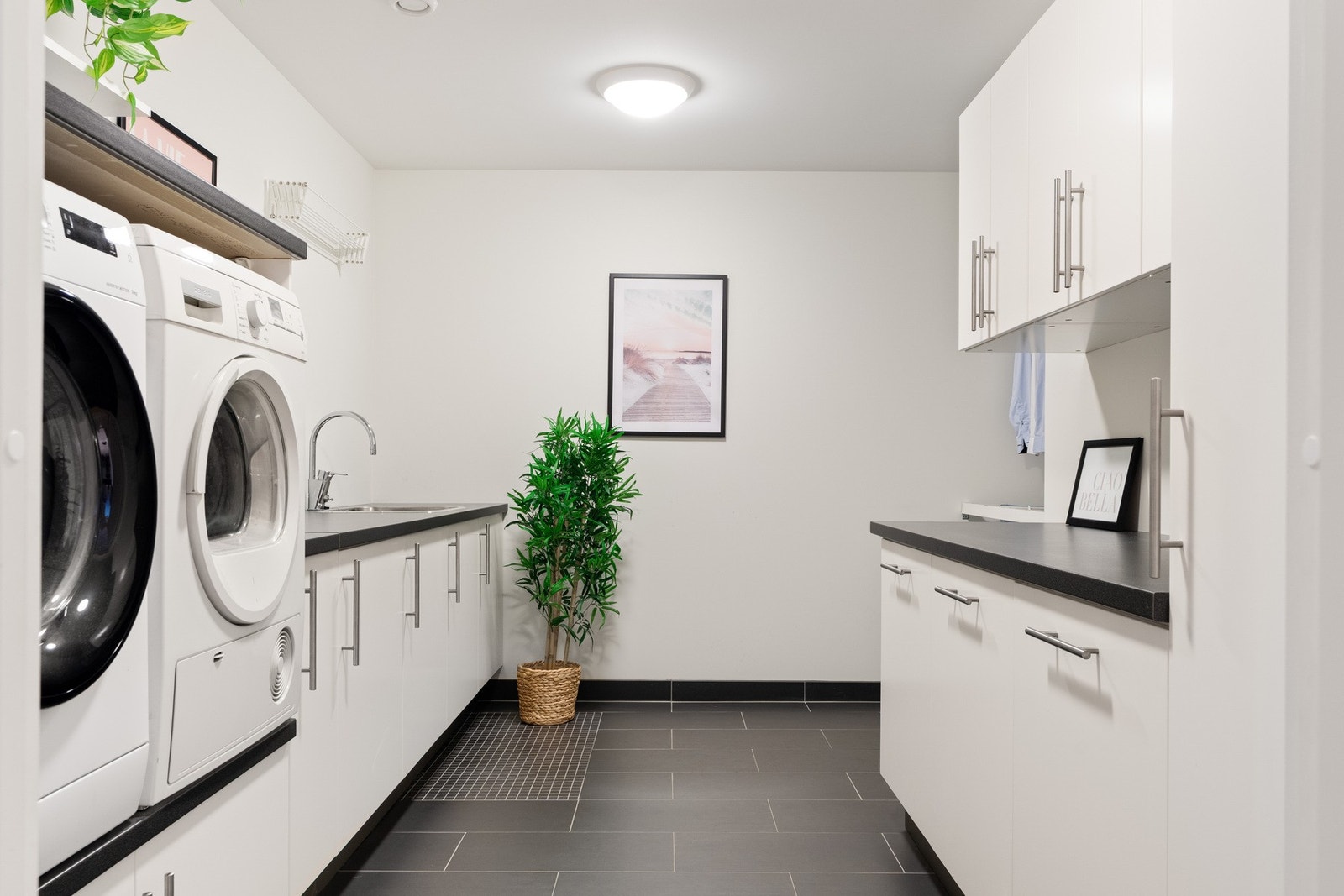 Rommet er praktisk innredet med egen tørkesone i enden av av vaskerommet, samt egen nisje for vaskemaskin og tørketrommel i god arbeidshøyde, og det er rikelig med skap- og benkeplass. Galleribilde