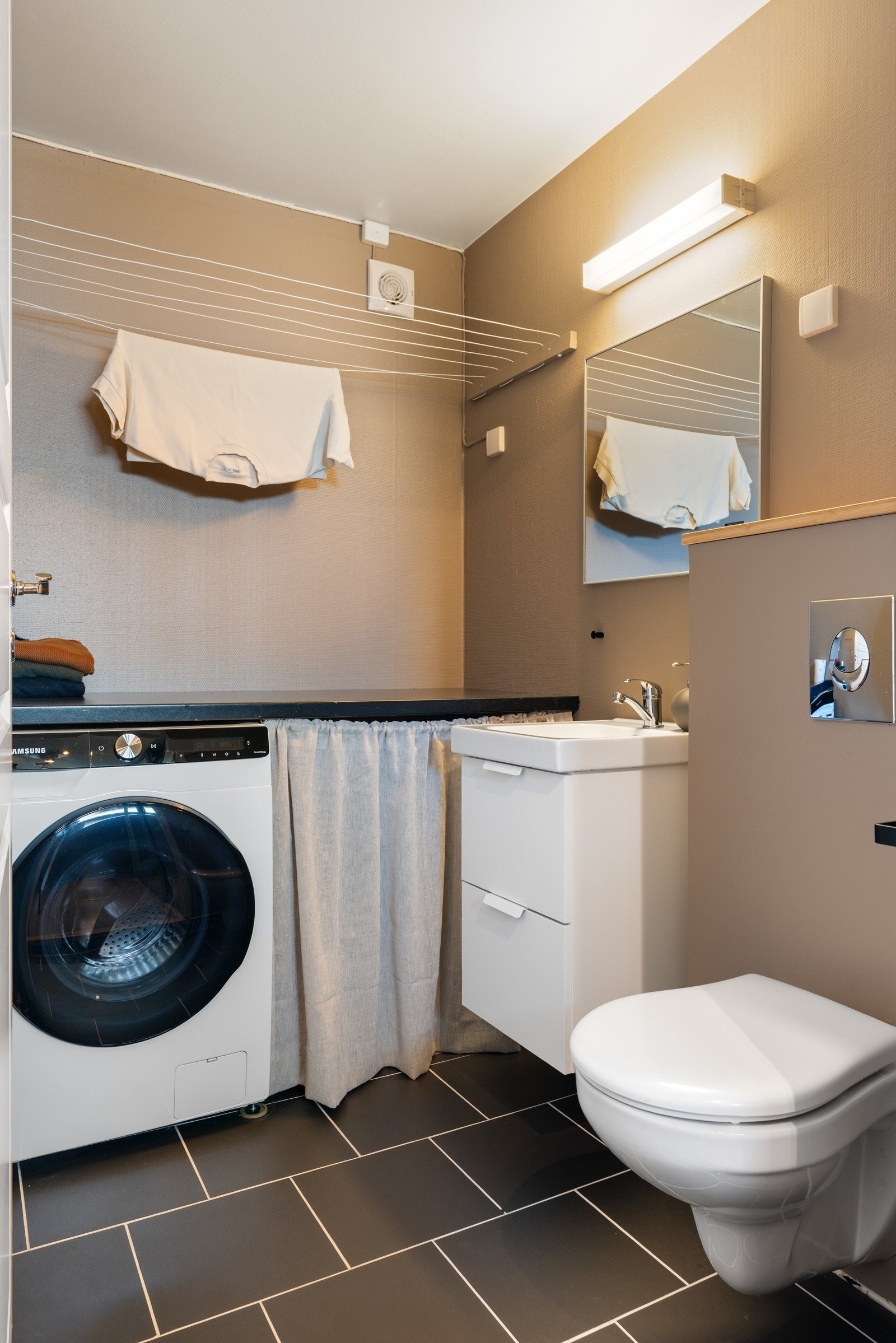 Vegg i vegg med entréen har man et praktisk vaskerom innredet med toalett, servant og opplegg for vaskemaskin. Galleribilde