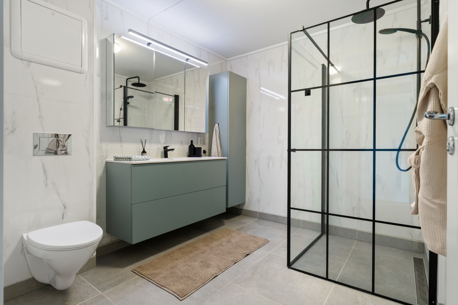 Baderommet måler 6,5 kvm og er utstyrt med dusjhjørne, vegghengt toalett og et pent baderomsmøbel med over- og underskap. Galleribilde