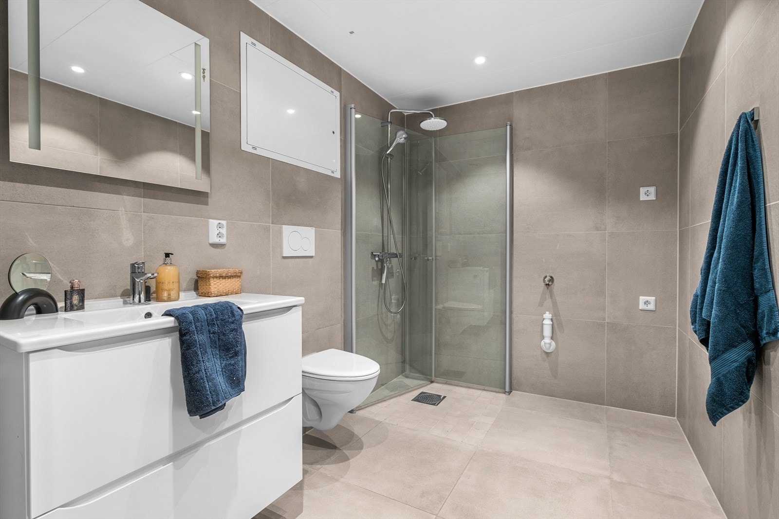 Det lekre flislagte badet er på 5,1m² og byr blant annet på behagelig gulvvarme. Badet er oppgradert med stilrene 60x60 vegg- og gulvfliser. Her er det innredet med innfellbare dusjdører, opplegg for vaskemaskin, veggmontert toalett- og innredet servant. Galleribilde