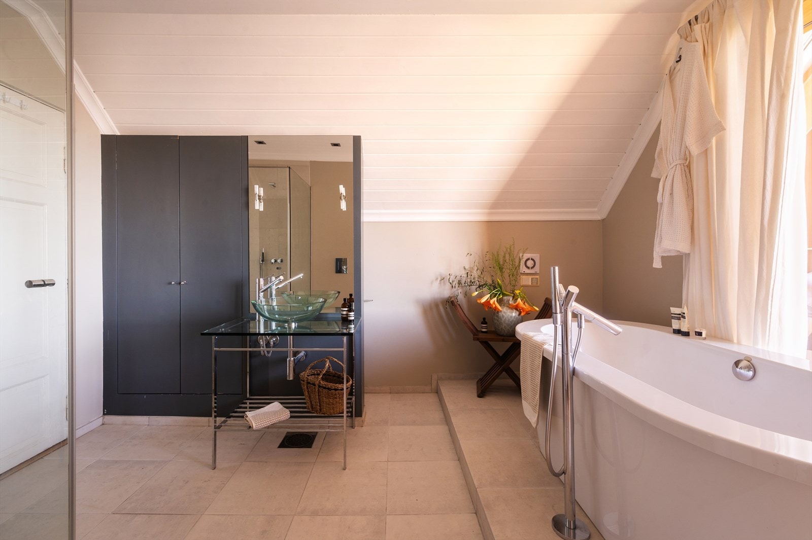 Badet er innredet med gulvmontert innredning med glassplate og ovenpåliggende servant med ett-greps armatur. Galleribilde