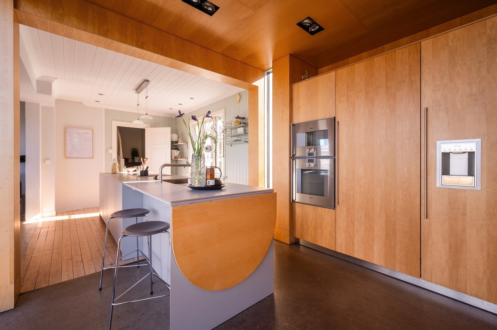 Stor kjøkkenøy med lysegrå fronter og laminat benkeplate. Galleribilde