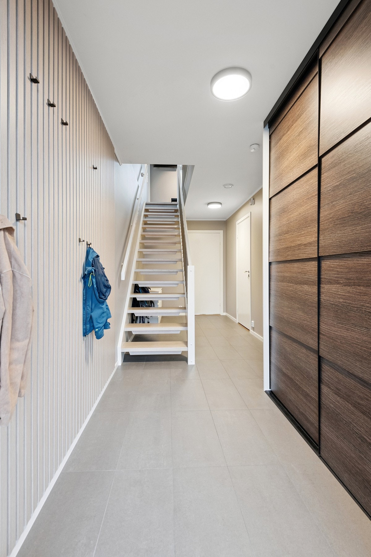 Flislagt gang med oppheng og praktisk skyvedørsgarderobe. Galleribilde