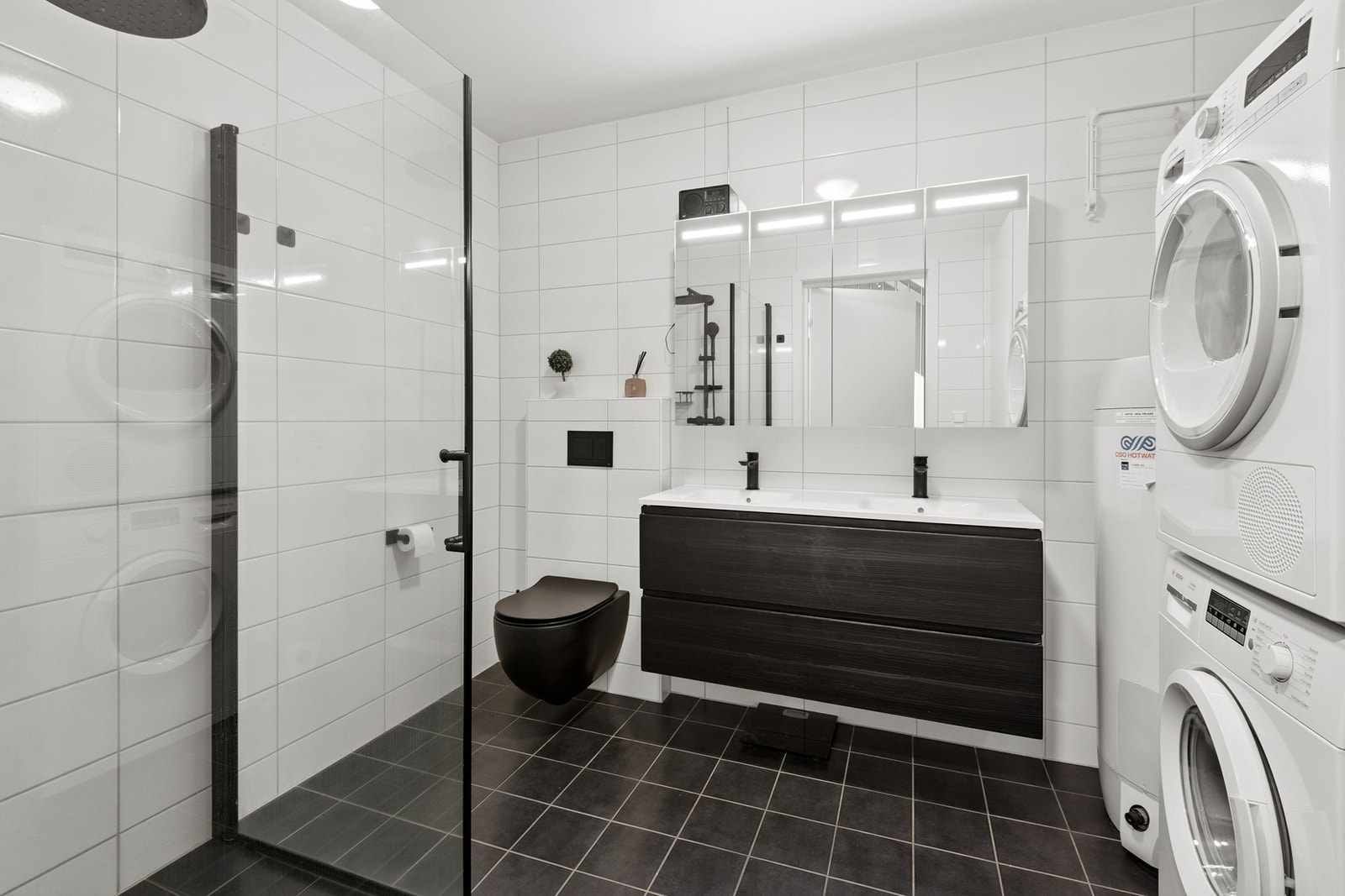 Badet har vegghengt toalett og praktisk dusjhjørne med glassdører. Galleribilde