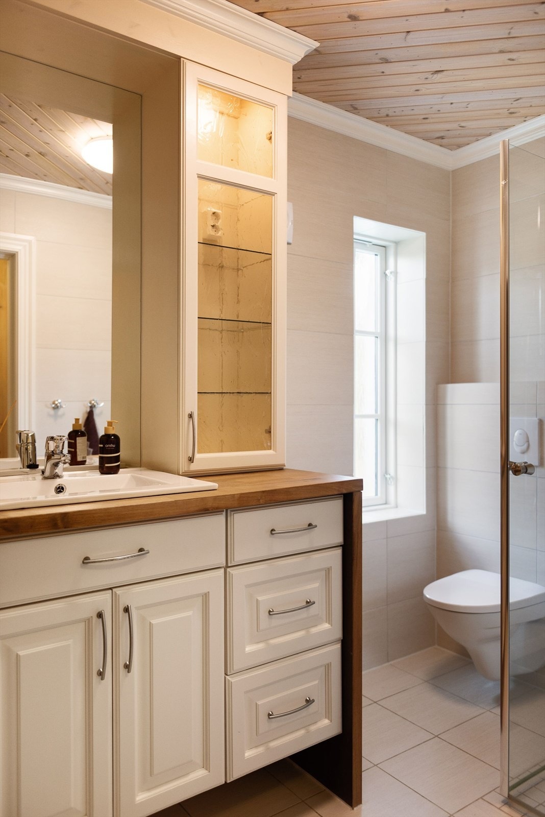 Flott baderomsinnredning med lyse fronter og heltre benkeplate med nedfelt servant. Baderommet er også utstyrt med dusjhjørne med glassdører og vegghengt toalett. Galleribilde