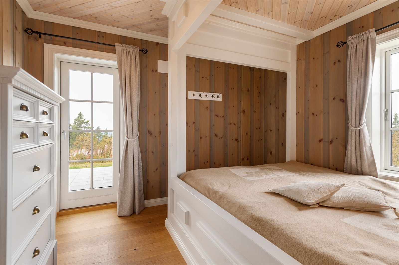 Hytta har et lyst og innbydende hovedsoverom med utgang til terrassen. Soverommet har flott plassbygget seng med fine detaljer. Galleribilde