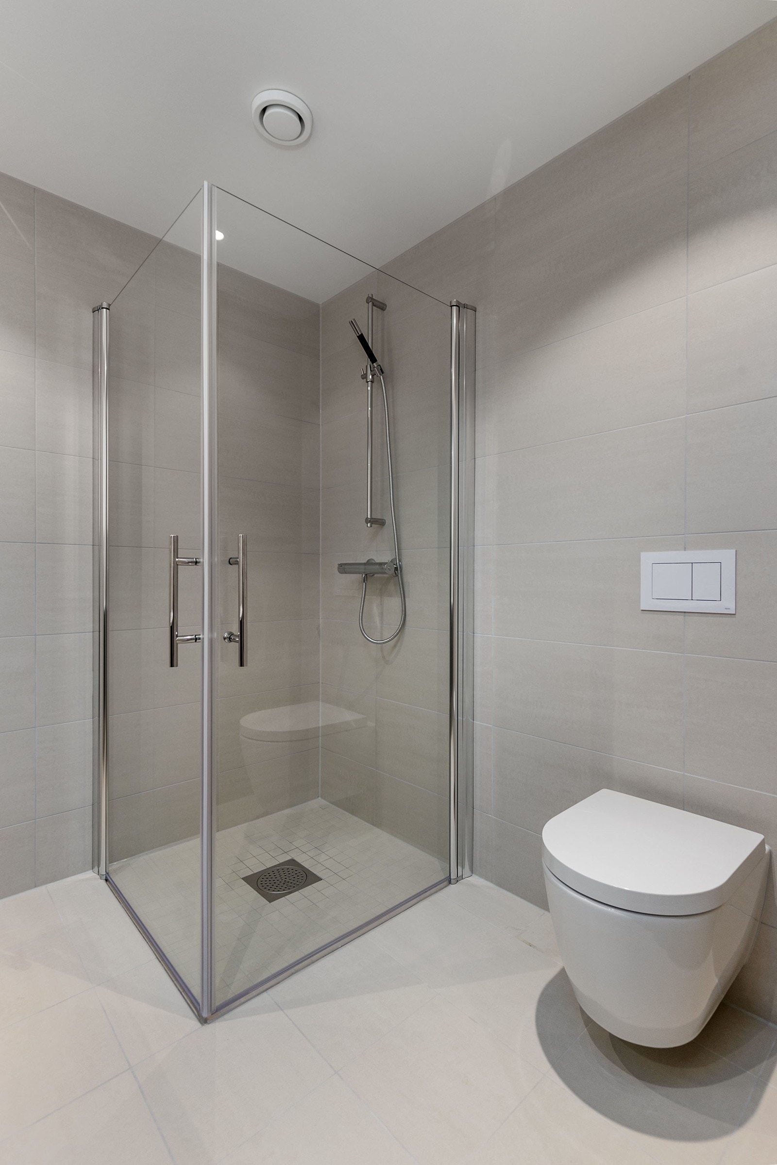 Rette dusjvegger i herdet glass, som kan slås inn mot vegg og med profiler i krom. Vegghengt toalett. Galleribilde
