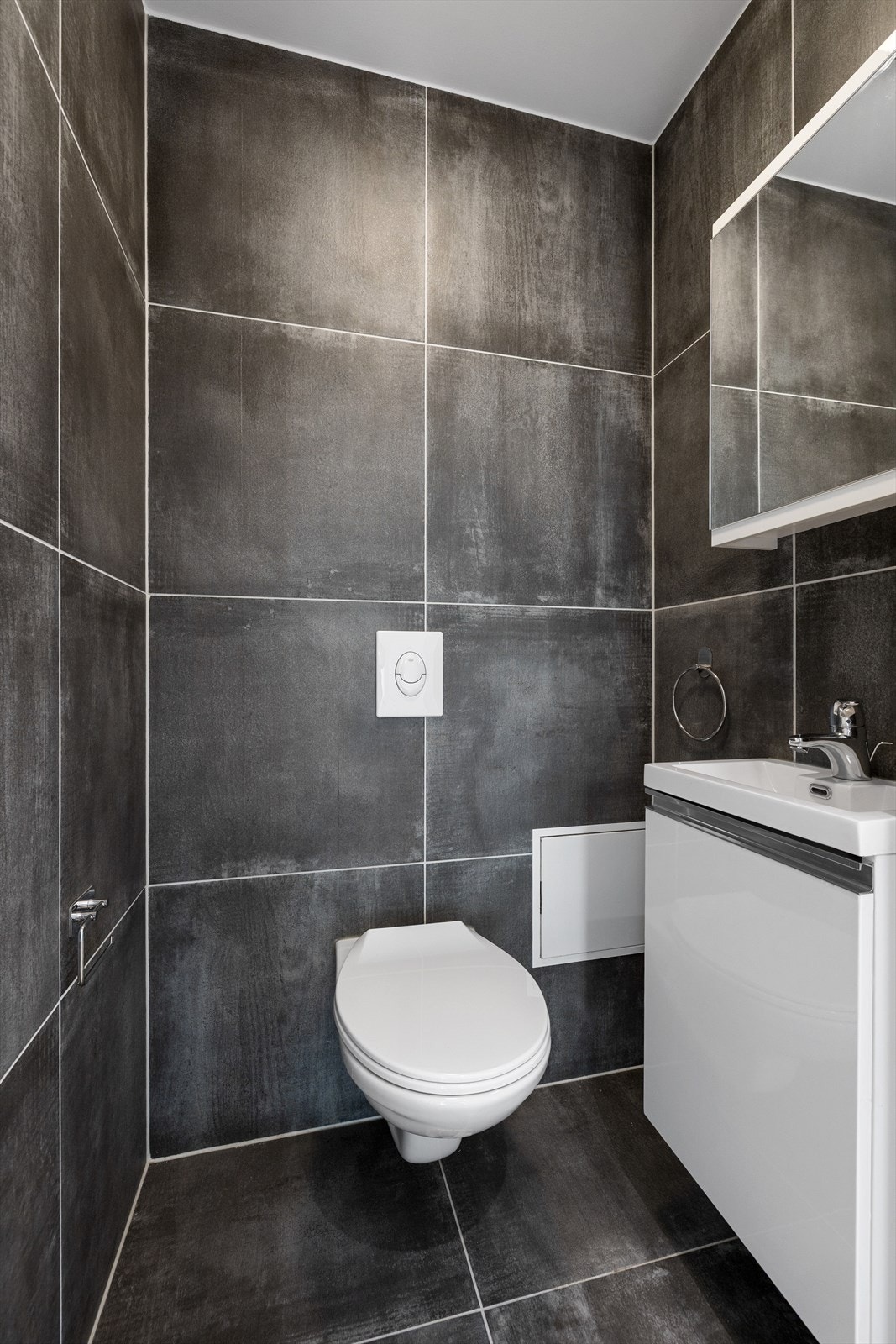 Toalettrommet er innbydende og funksjonelt, med fliser på både gulv og vegger som gir et eksklusivt og lettstelt uttrykk. Himlingen er utført med malte plater for et rent og moderne preg. Galleribilde