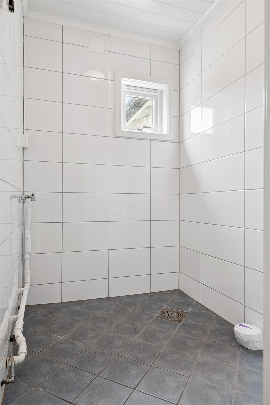 Praktisk, flislagt vaskerom med opplegg for vaskemaskin, sluk og varmekabler i gulvet. Galleribilde