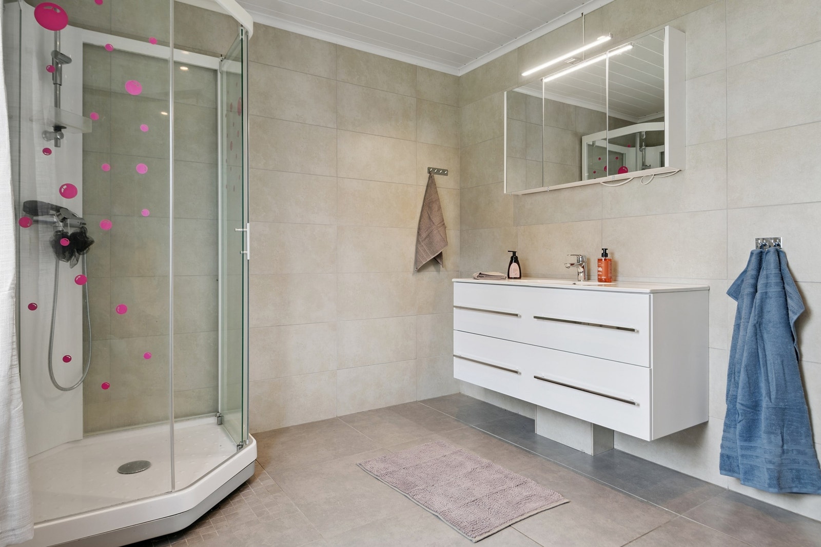 Badet i første etasje er flislagt og utstyrt med dusjkabinett og en moderne baderomsinnredning. Galleribilde