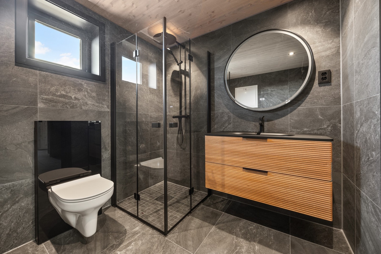 Badet er holdt i delikate flis- og materialvalg. Downlights. Utstyrt med servantskap, toalett og dusj Galleribilde