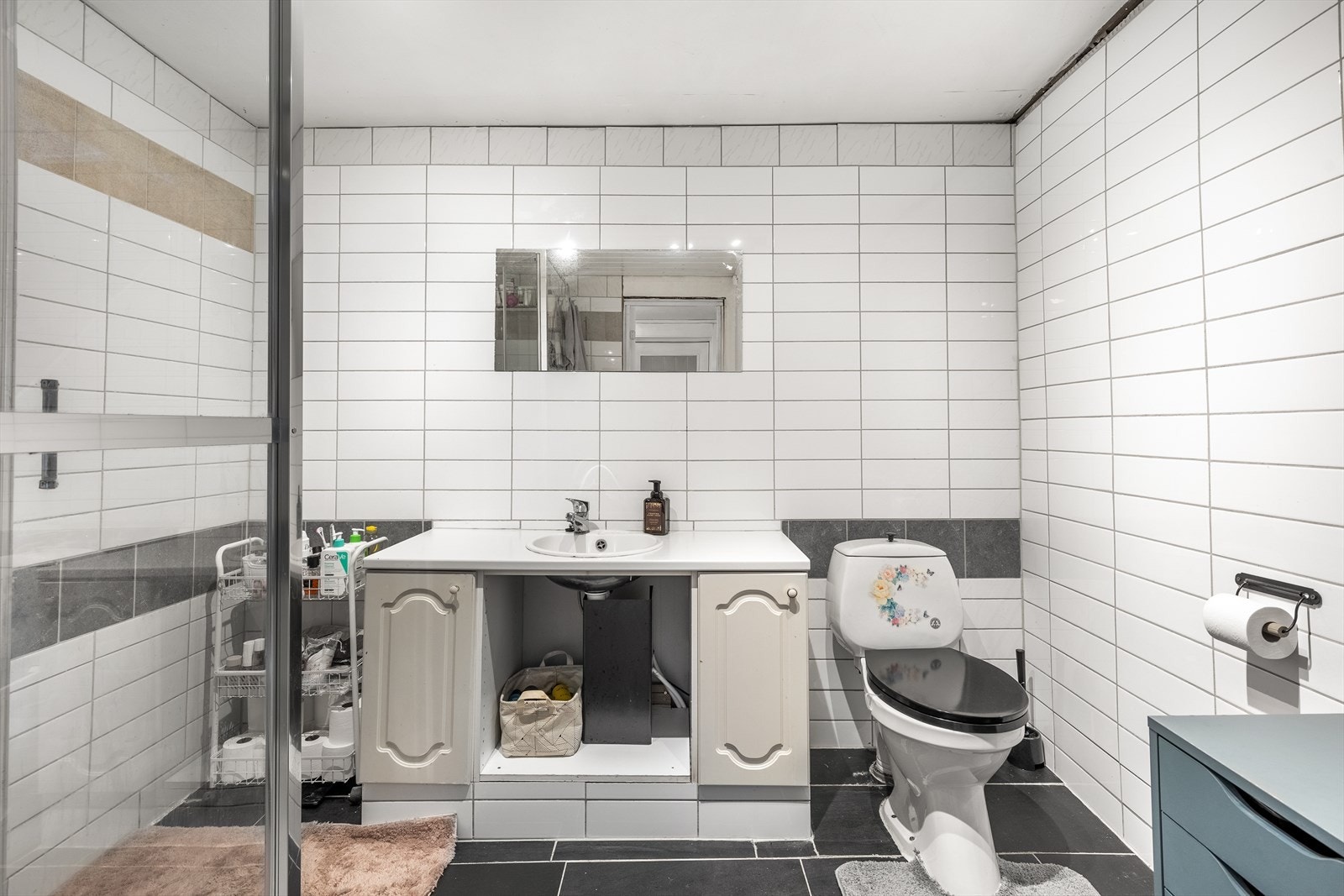 Bad er innredet med servantinnredning, toalett og dusjkabinett Galleribilde