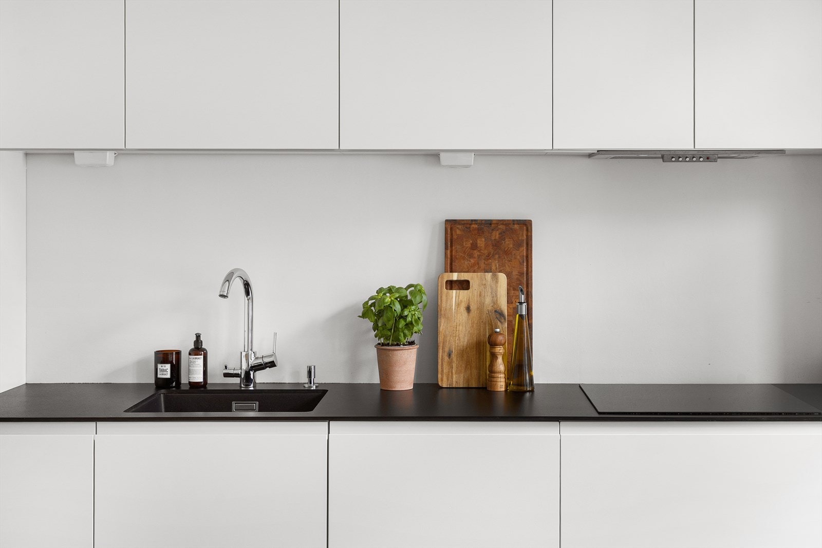 Innredningen har lyse matte fronter, benkeplate i laminat, sort underlimt oppvaskkum, ventilator og integrerte hvitevarer. Galleribilde