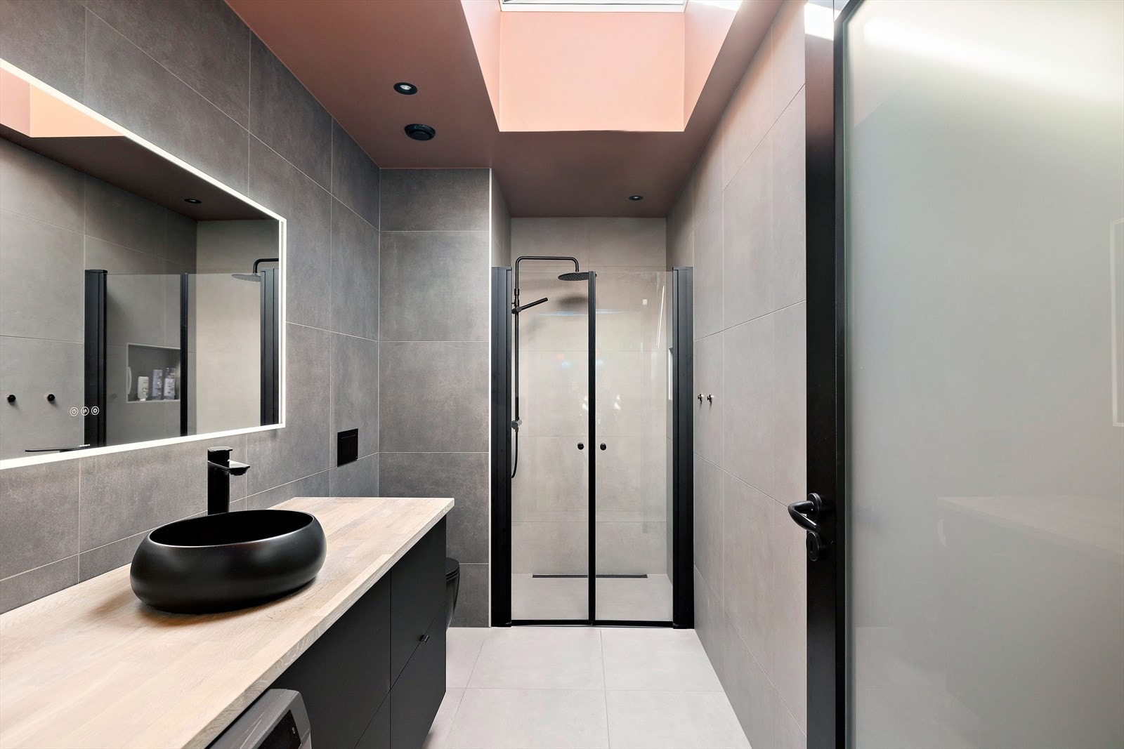 Innbydende helfliset bad med varmekabler i gulv. Vegghengt toalett og dusjhjørne med innfellbare glassvegger. Galleribilde