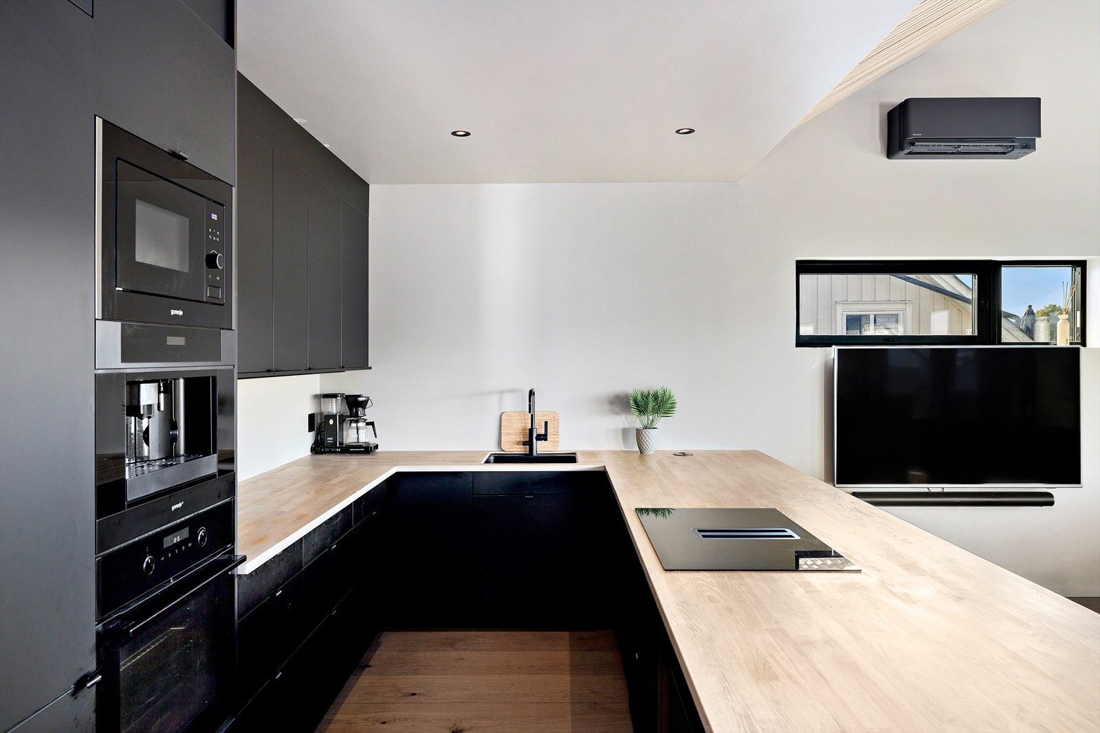 Delikat kjøkken med sorte, slette fronter og rikelig med skap- og benkeplass. Galleribilde