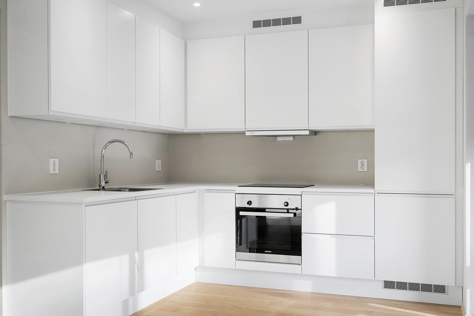 Kjøkkeninnredning med slette lyse fronter og benkeplater Galleribilde