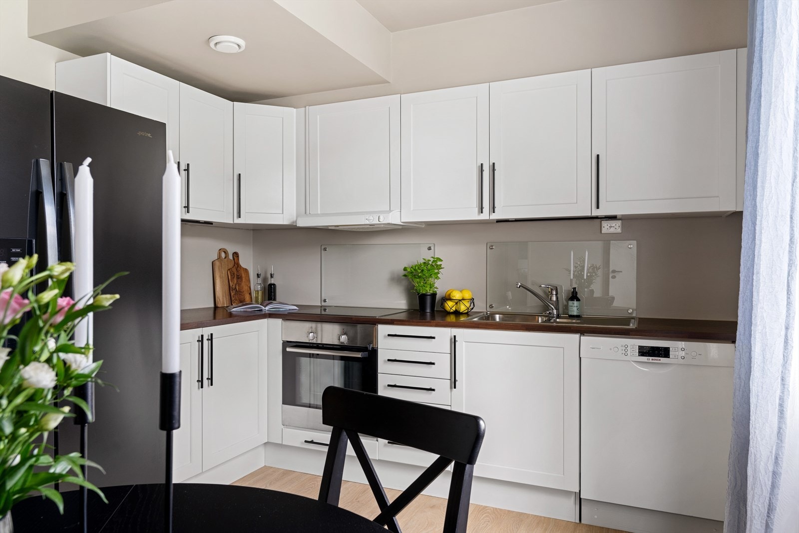 Lys og lekker kjøkkeninnredning med tidløst preg og integrert komfyr, platetopp og oppvaskmaskin. Galleribilde