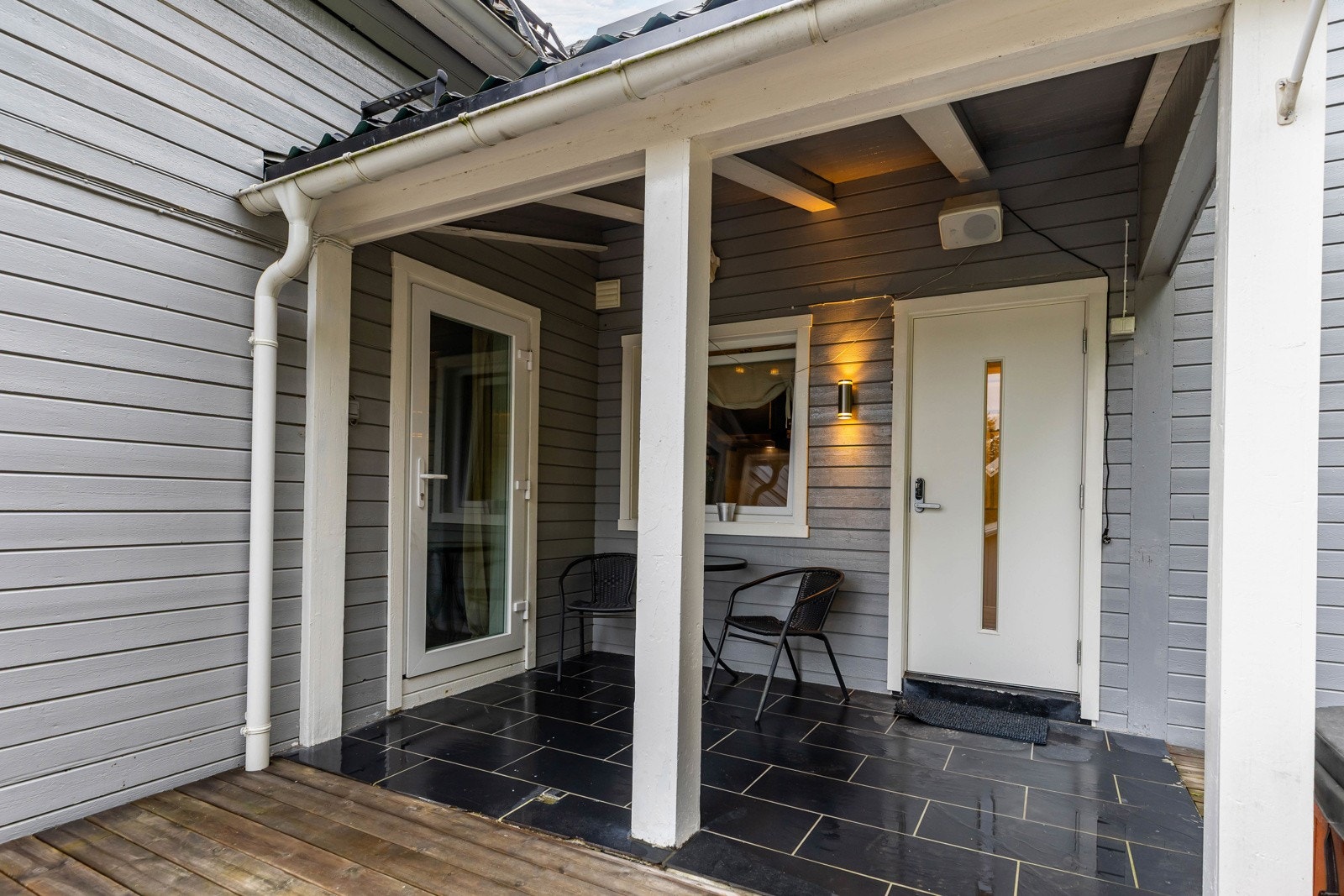 Overbygget inngangsparti med flislagt terrasse og plass til sittegruppe. Galleribilde