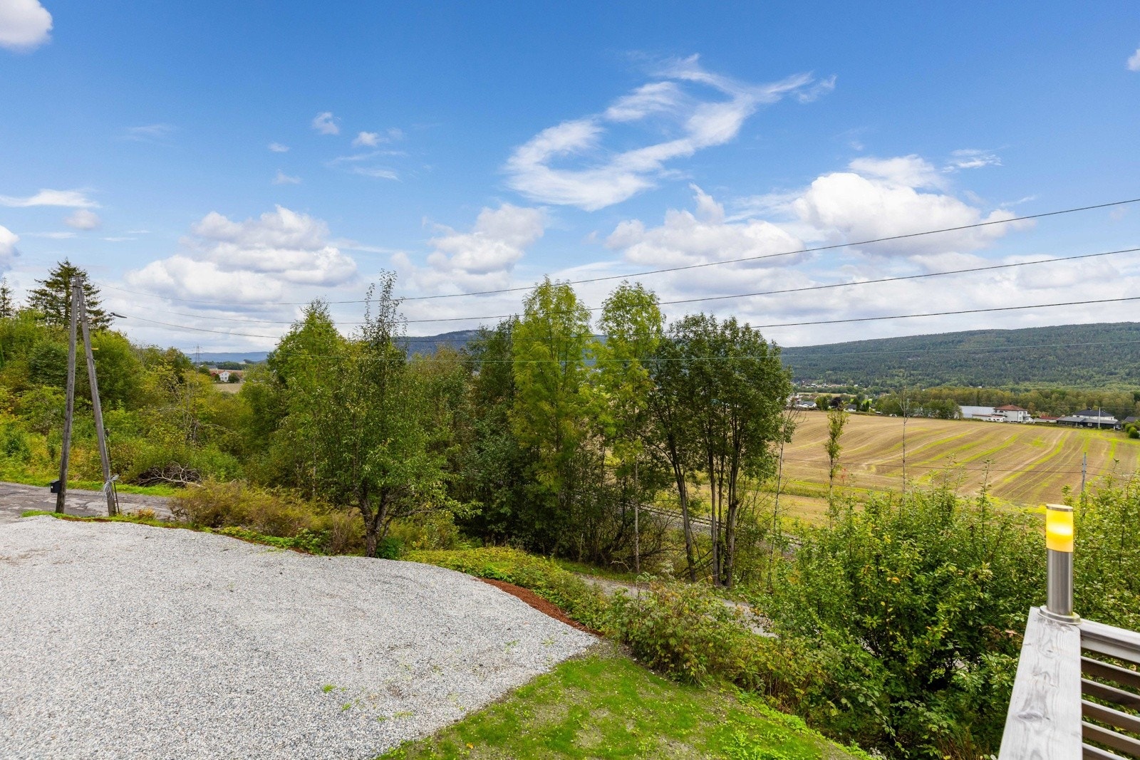Gruset gårdsplass og utsikt oppover eikerbygdene. Galleribilde