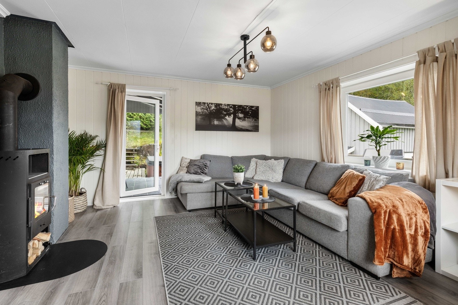 Lys og innbydende stue med vedovn, store vinduer og utgang til veranda. Galleribilde