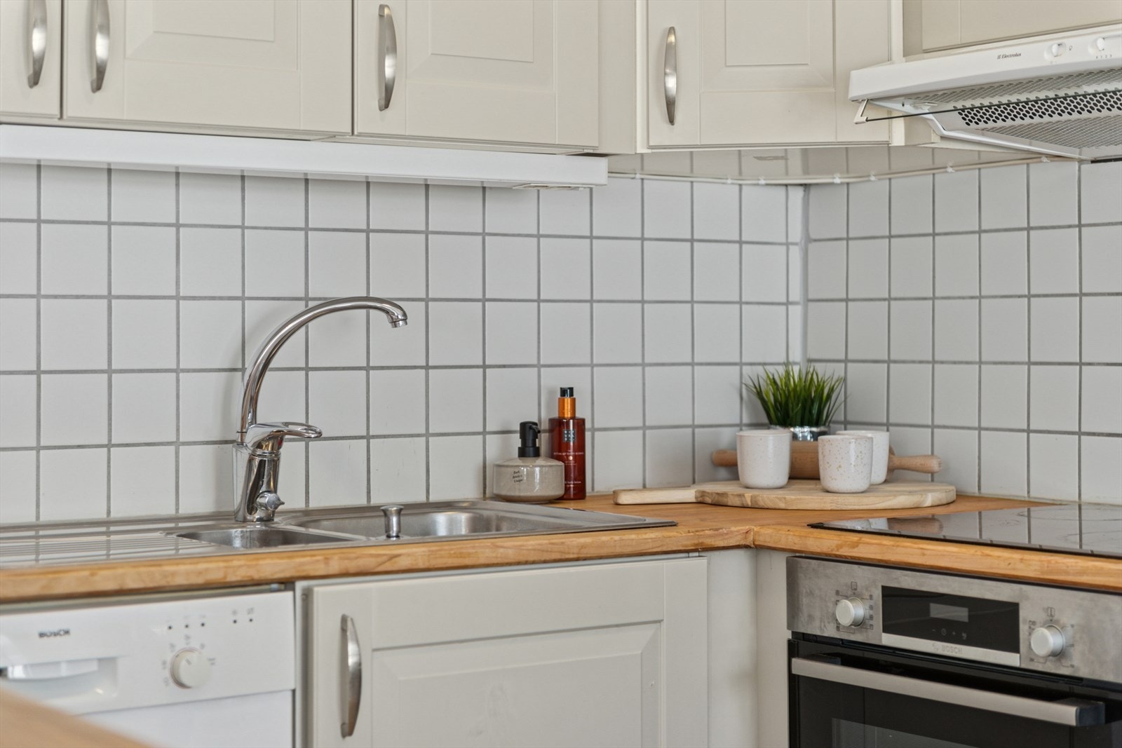 Bakveggen i arbeidssonen på kjøkkenet er flislagt for enklere rengjøring | Intergret komfyr og platetopp. Galleribilde