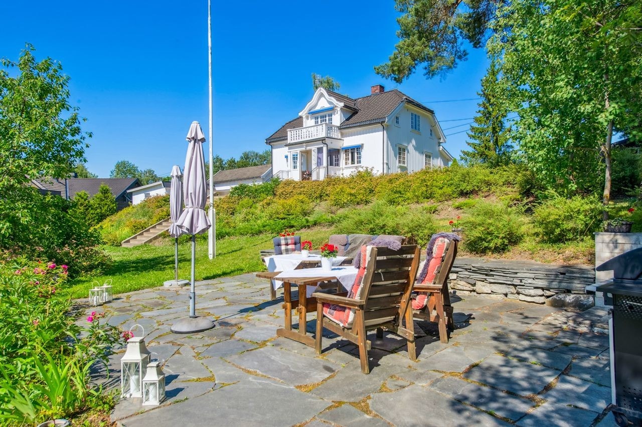 En solrik og idyllisk uteplass i hagen med skiferheller hvor utelivet kan nytes i sommerhalvåret. Galleribilde