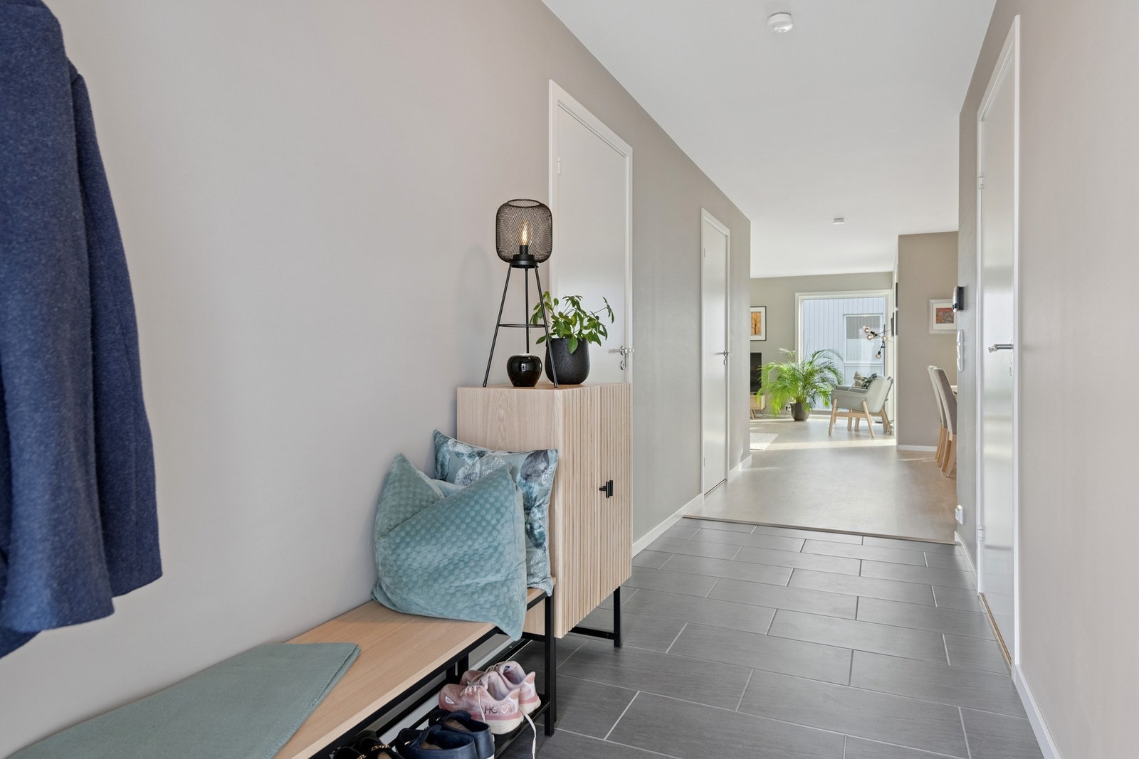 Innbydende gang med flis på gulv og plass til å henge fra seg klær og sette sko. Galleribilde