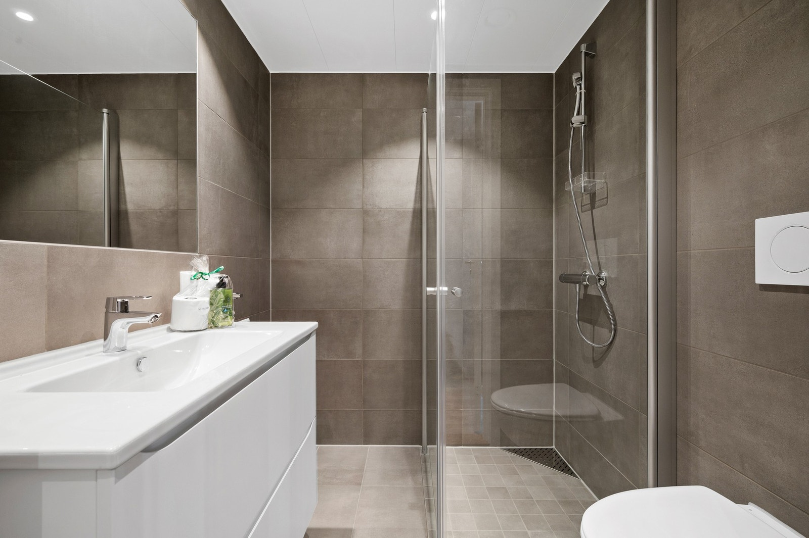 Stilig og flislagt bad på ca 3,2kvm. Badet er utstyrt med servant m/lagring, vegghengt toalett og et dusjhjørne. Galleribilde