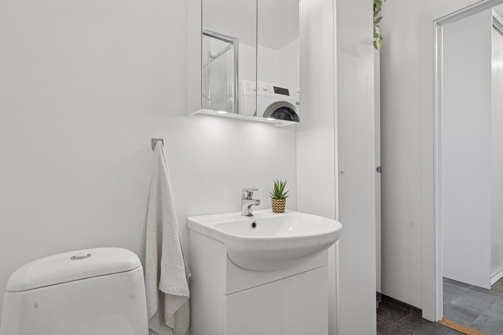 Baderom med servant med skap under, det er speilskap og ett ekstra skap. Galleribilde