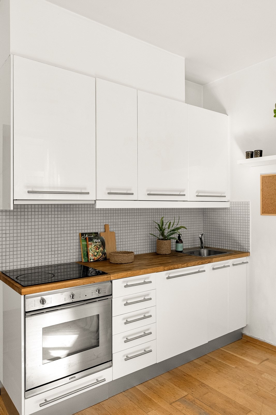 Kjøkken i åpen løsning mot stue med høyglanset fronter og benkeplate i tre. Galleribilde