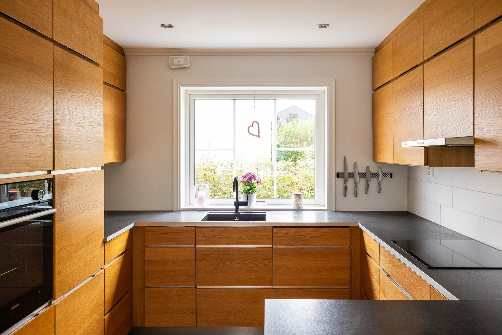 Innredningen har slette fronter i treverk som gir et varmt preg, mens laminatbenker og fliser over benk gir et moderne uttrykk. Galleribilde