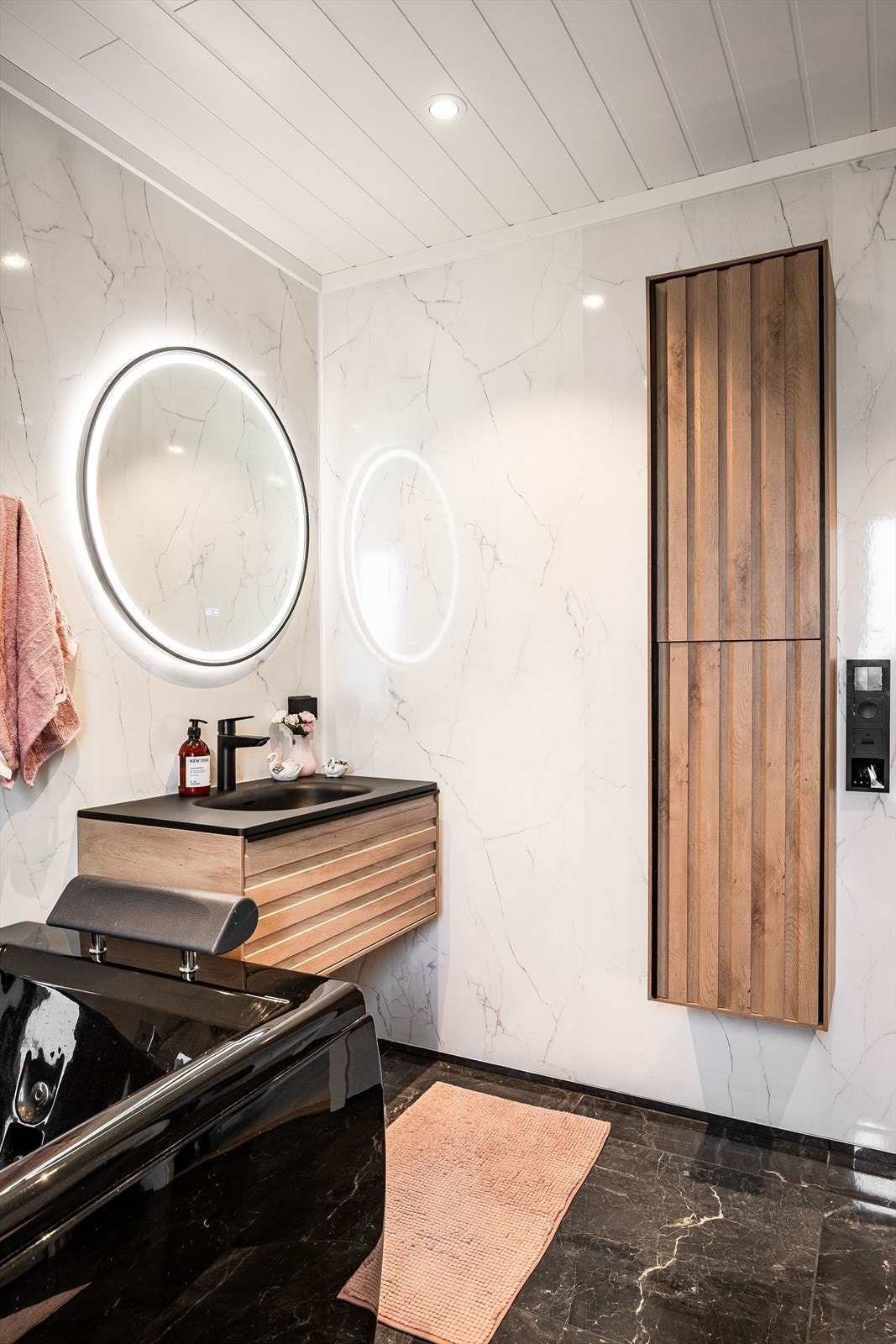 Stilig innredning med heldekkende sort servant, rundt speil med integrert belysning over. Baderommet er også utstyrt med ekstra vegghengt skap, boblebadekar, dusjkabinett og vegghengt toalett. Galleribilde