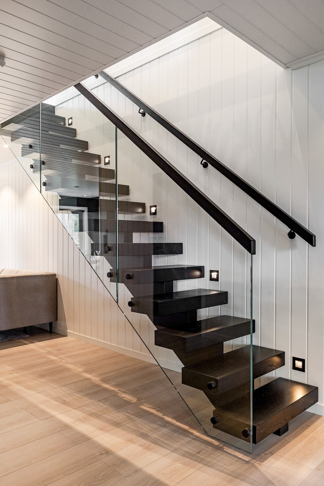 Stilig trapp med glassrekkverk og innfelt belysning ved trappetrinnene. Galleribilde