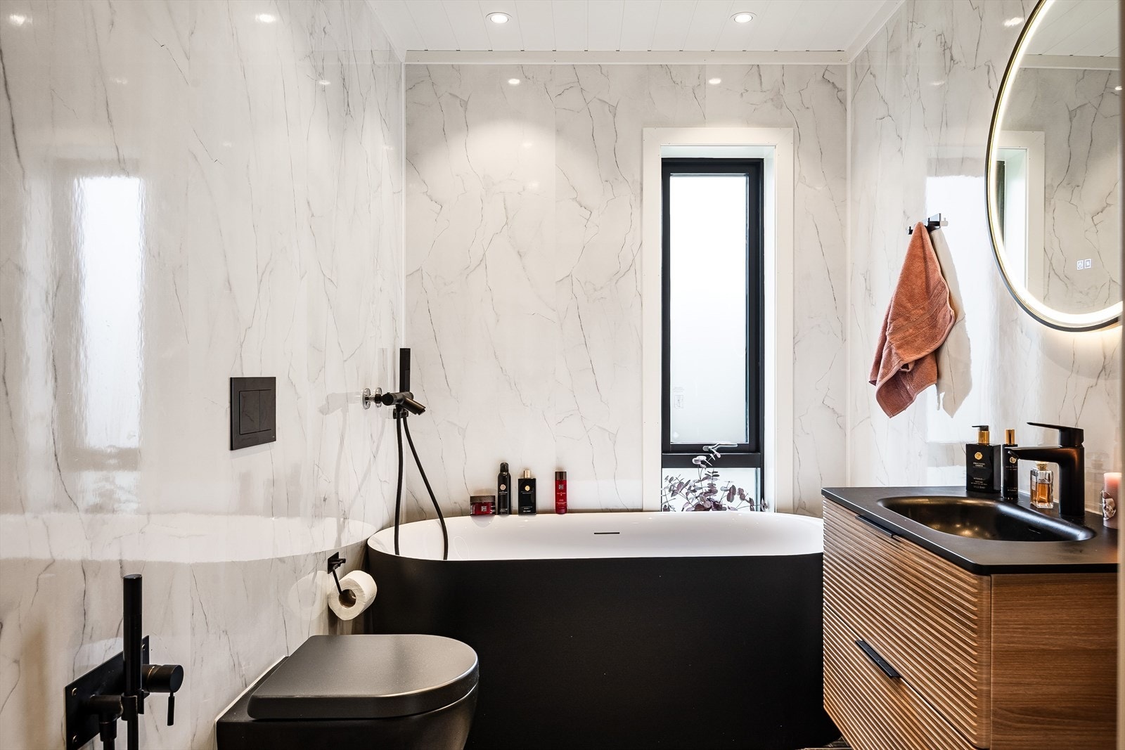 Lyst og lekkert baderom med flotte fliser på gulv, vannbåren gulvvarme, delikate våtromsplater på veggene, downlights i himlingen og avtrekk via balansert ventilasjon. Galleribilde