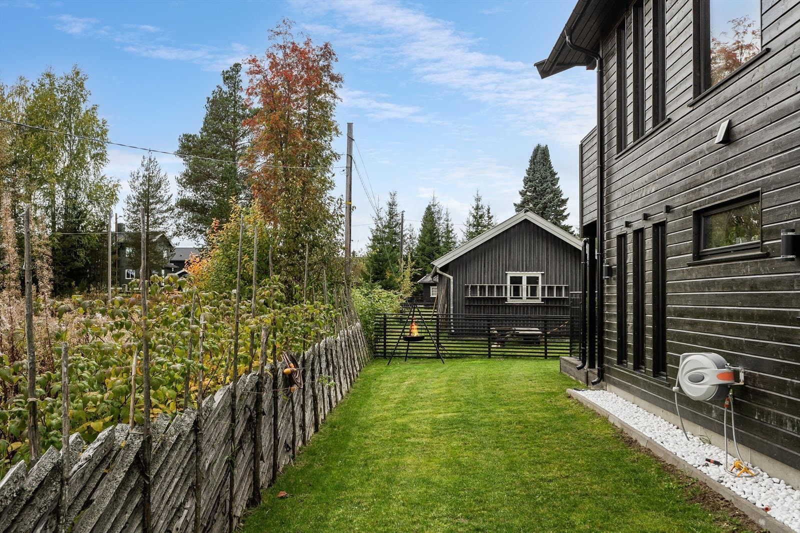 Hyggelig hage opparbeidet med plen og lys dekorstein langs husveggen. Hagen er delvis inngjerdet met skigard og gjerde. Galleribilde