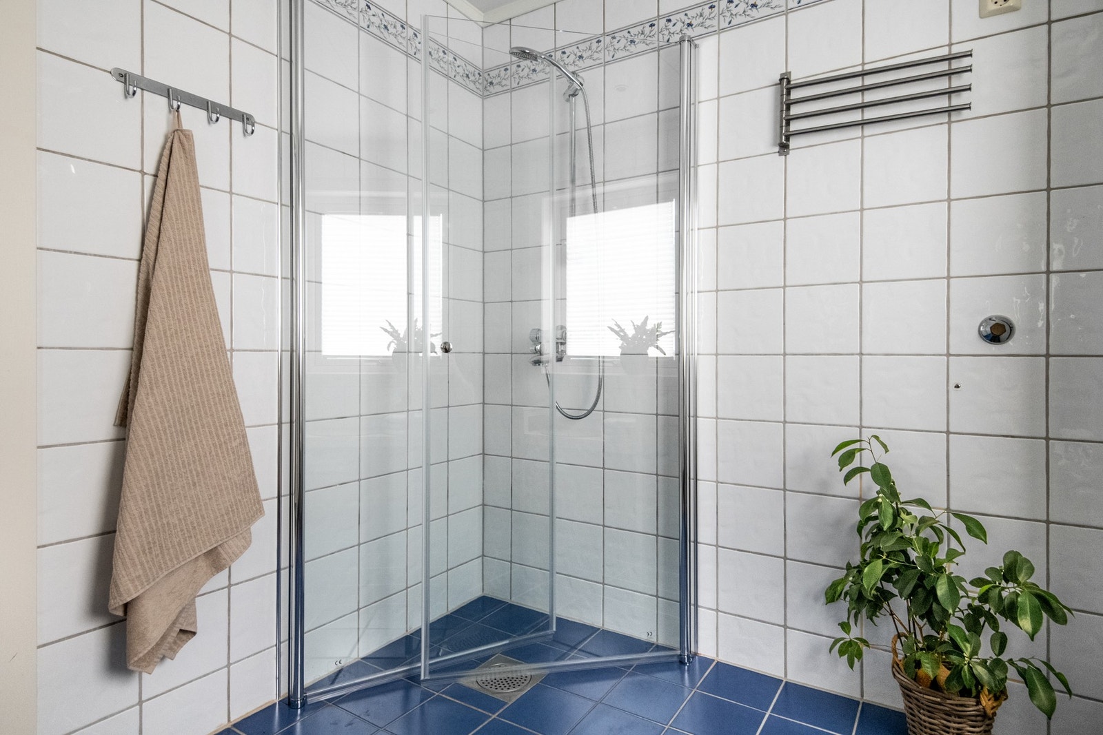 Innredning med benkeskap og veggskap med profilerte fronter, høyskap med frostet glassfront, speil og belysning over servant og dusj med glassdører. Galleribilde