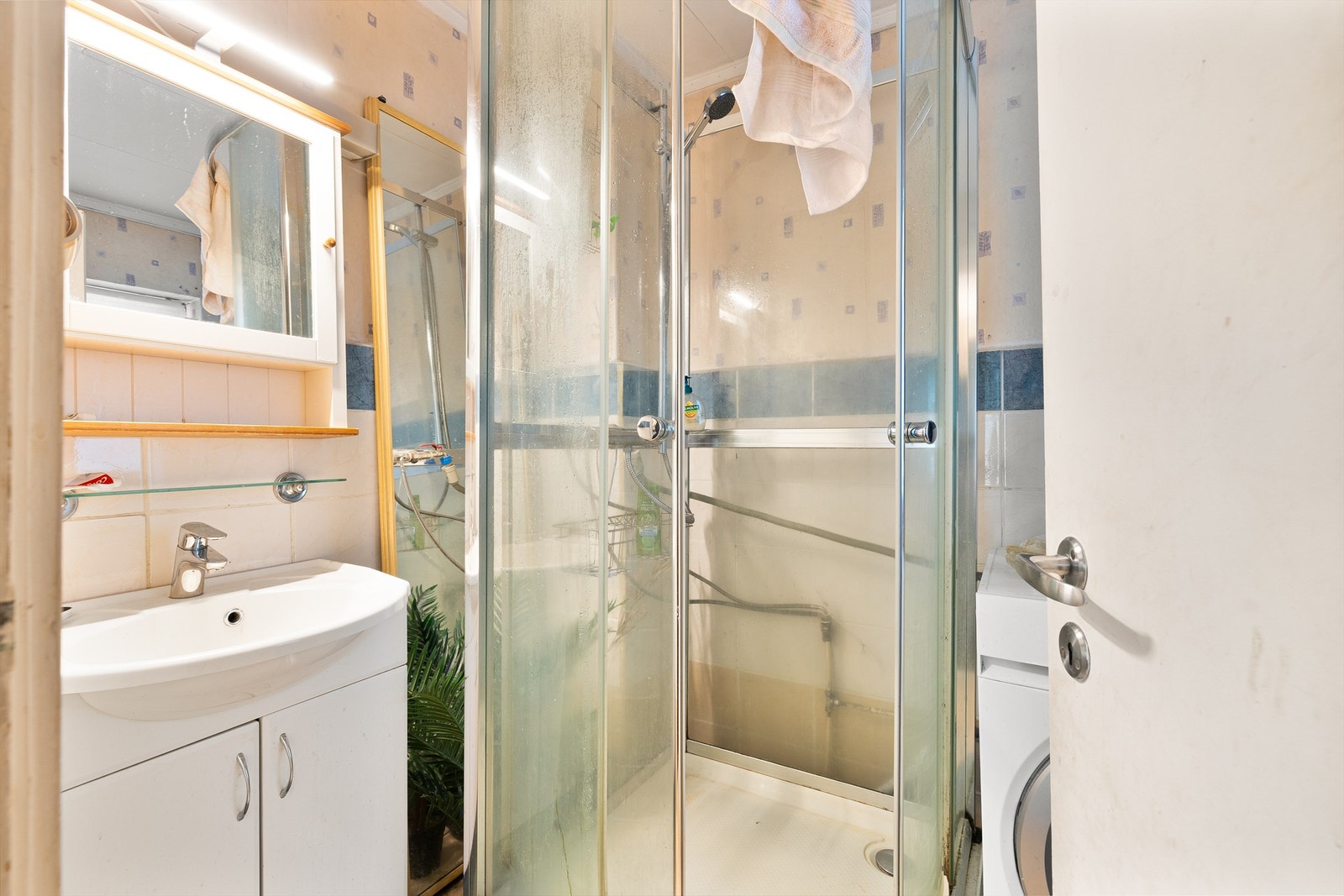 Lyst bad med dusjkabinett, opplegg for vaskemaskin og servant. Galleribilde