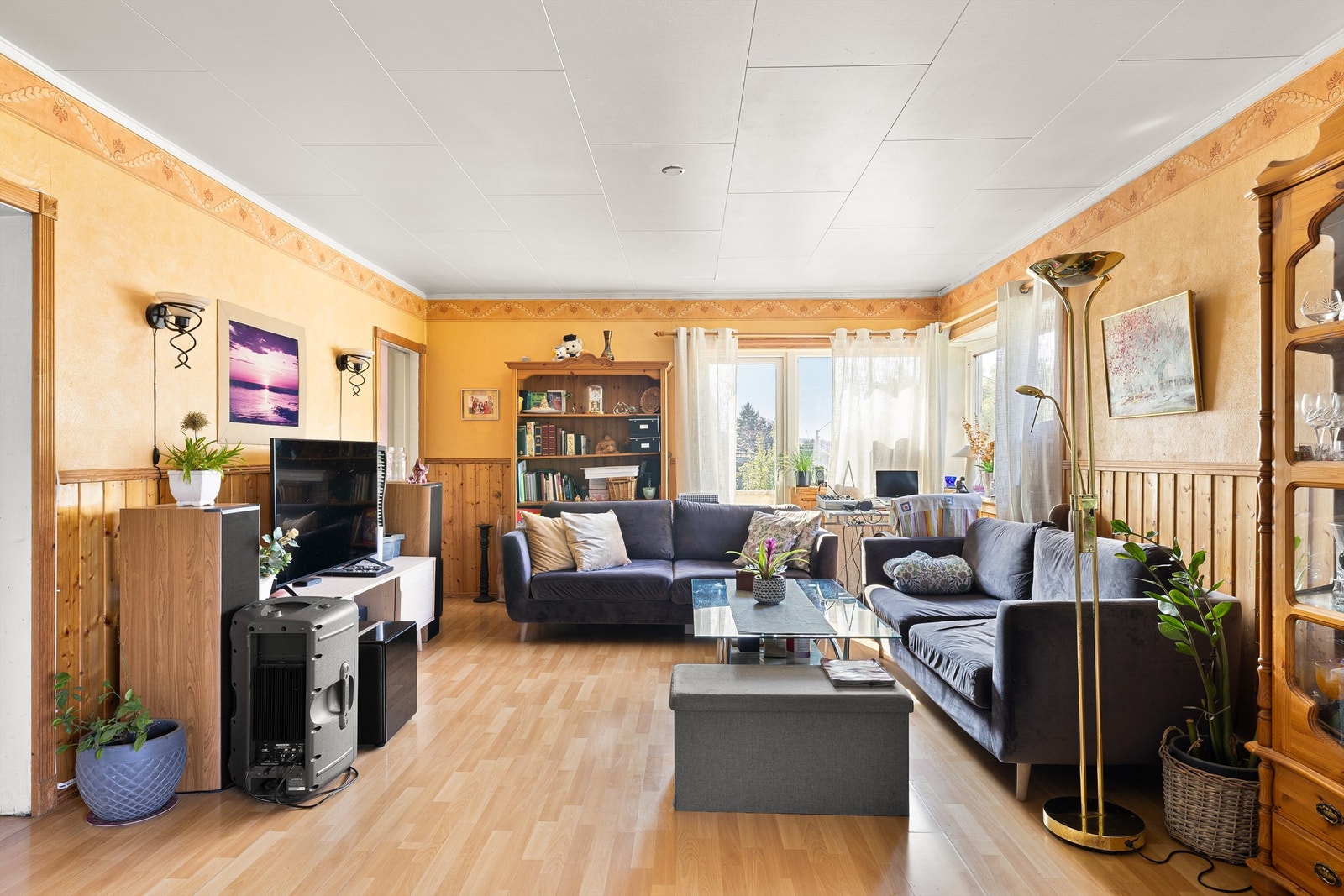 Lys stue med store vinduer som rammer inn grønt utsyn, behagelig takhøyde og god romfølelse. Galleribilde