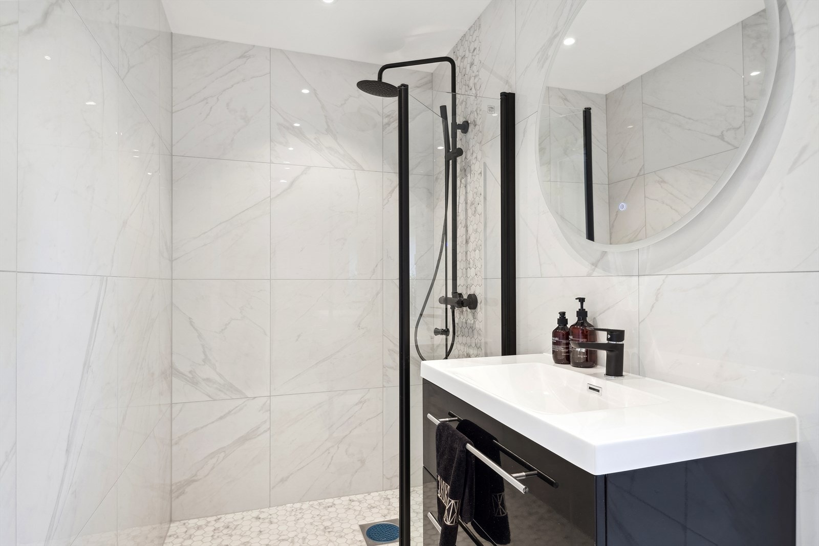 Badet er helt nytt og er ubrukt. Baderomsinnredningen består av flislagt gulv, dusjhjørne med nedsenk i dusj og innsvingbare dører, dusj direkte på gulv, veggmontert klosett og formstøpt servant. Galleribilde