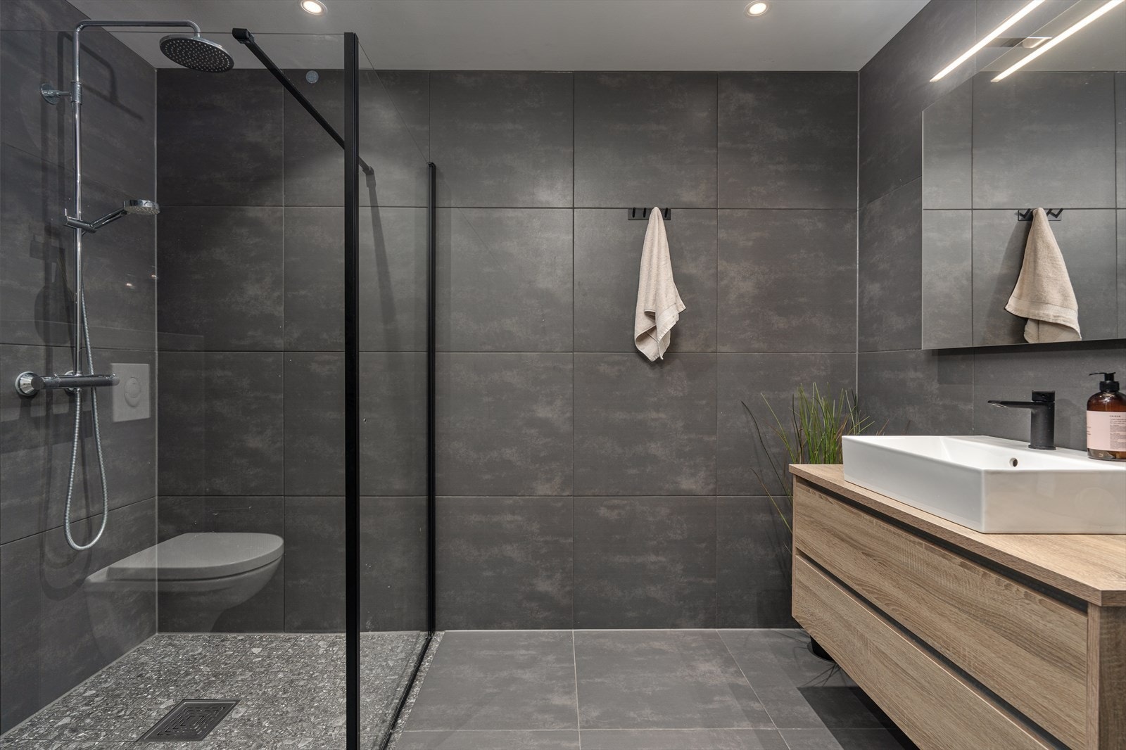 Lekkert baderom av god størrelse som er innredet med dusjhjørne, baderomsinnredning med servant og veggmontert toalett. Galleribilde