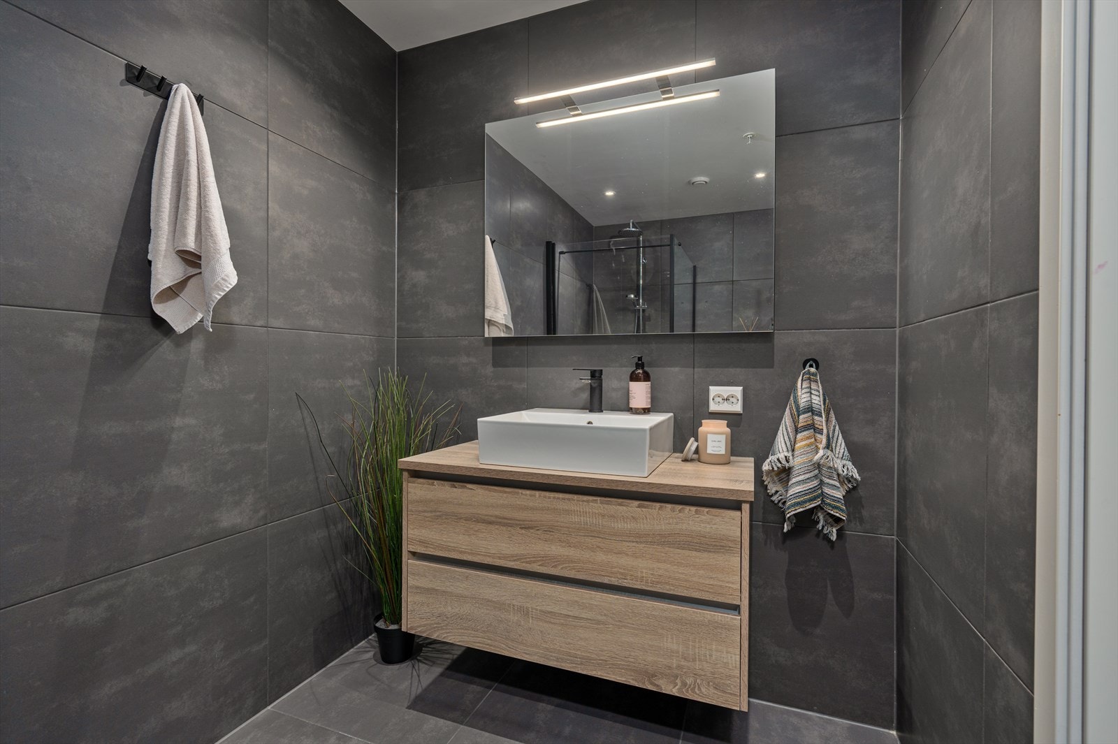 Rommet har fliser på vegger og malte overflater/plater i tak. Flislagt gulv med varmekabler. Leiligheten har også separat vaskerom og gjestetoalett. Galleribilde