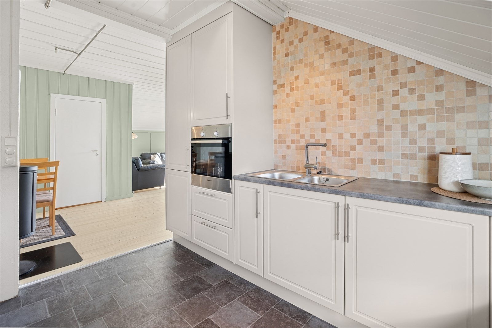 Delikat kjøkken med hvite profilerte fronter og laminat benkeplate med oppvaskkum. Galleribilde