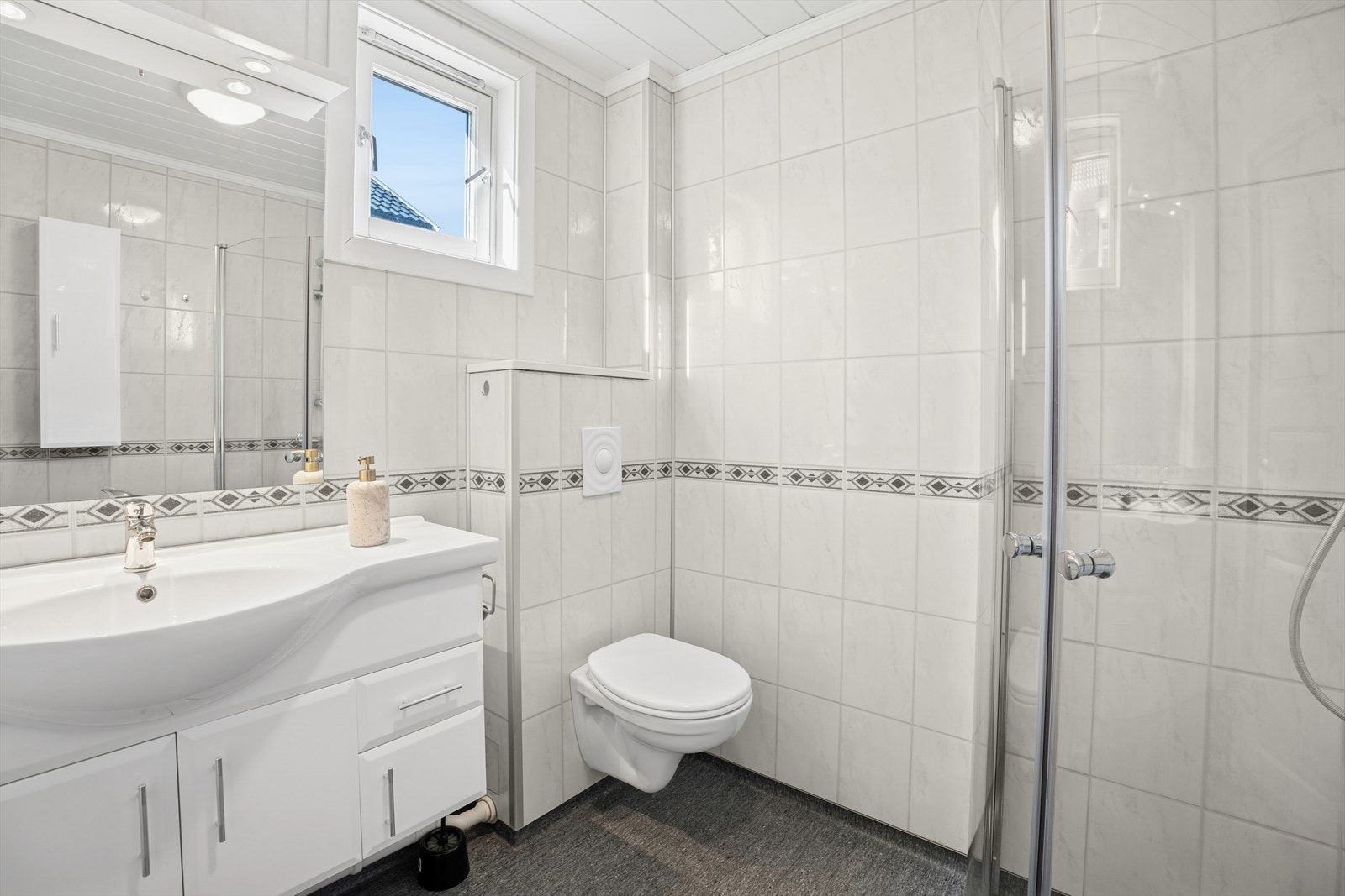 Rommet har innredning med nedfelt servant, veggmontert toalett, dusjvegger/hjørne og opplegg for vaskemaskin. Galleribilde