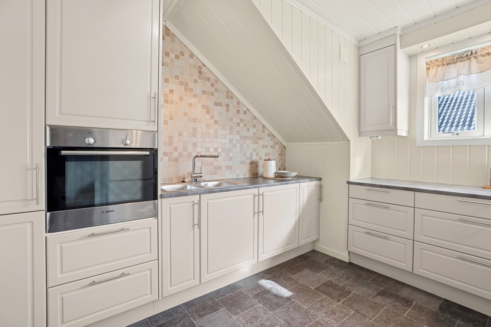 Det er integrert platetopp og stekeovn, samt frittstående kjøleskap. Galleribilde